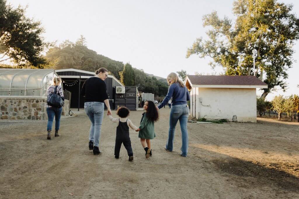 Family with young children holding hands while walking