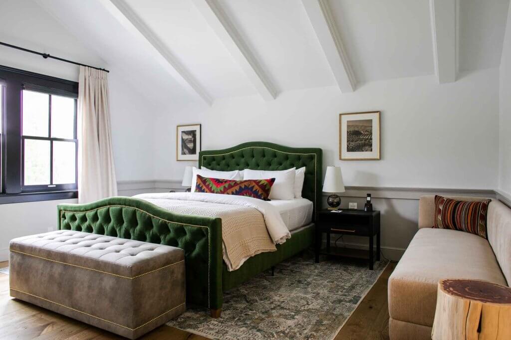 A bed with a green upholstered headboard.